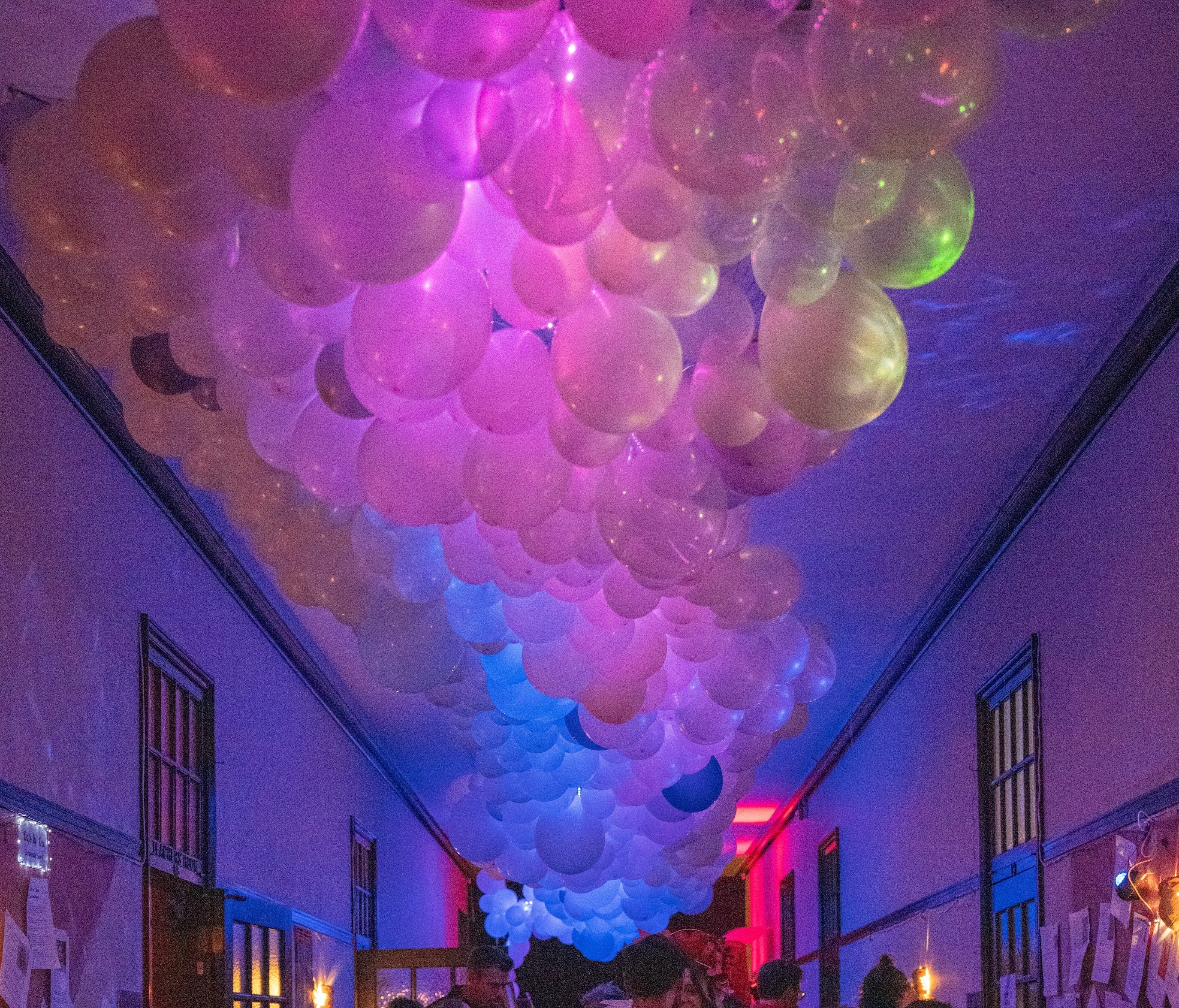 Illuminated balloon river installation filling a warehouse hallway with soft lavender and purple light
