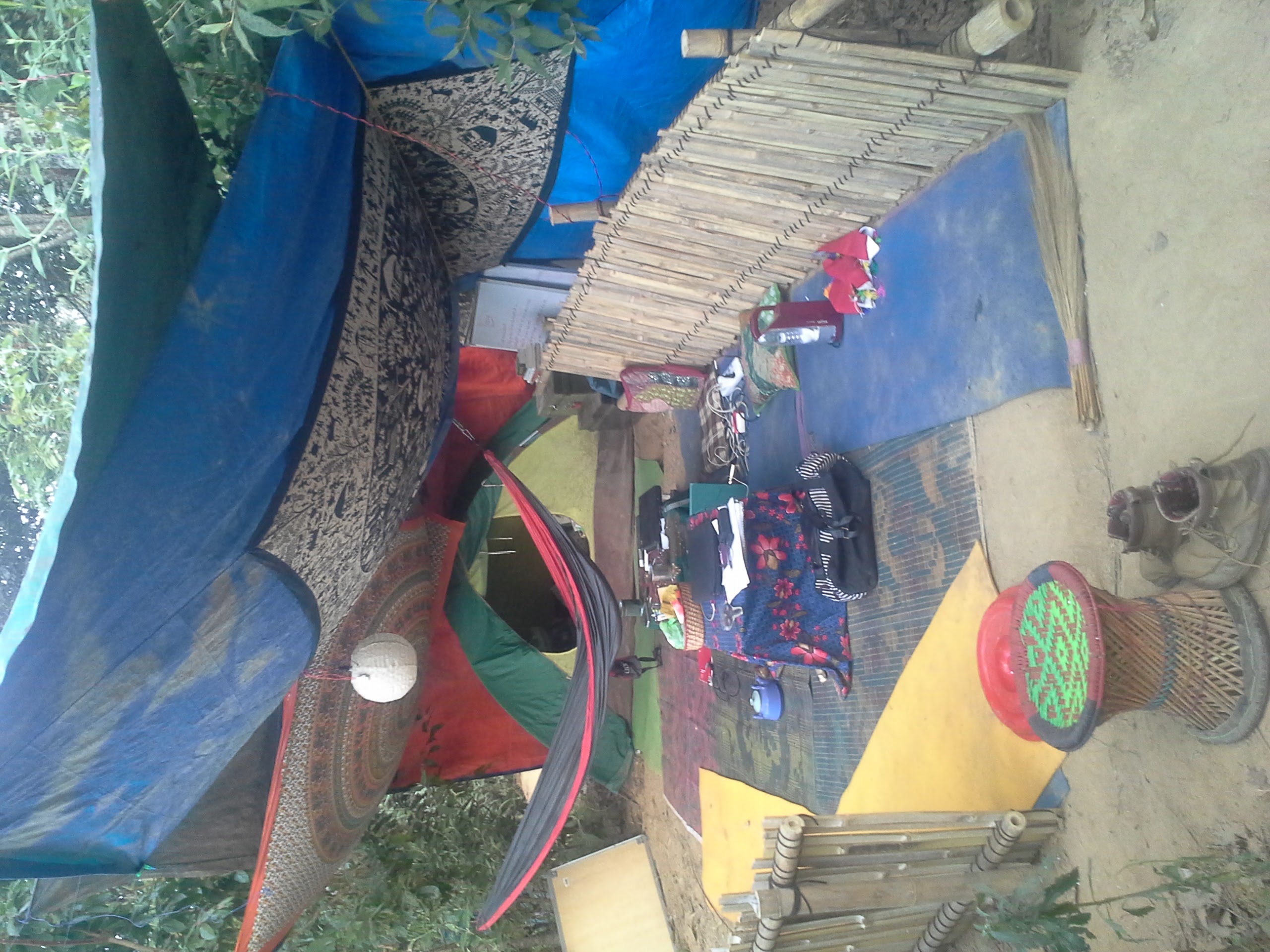 Low bamboo wall surrounding an outdoor meeting space with carpets and cushions
