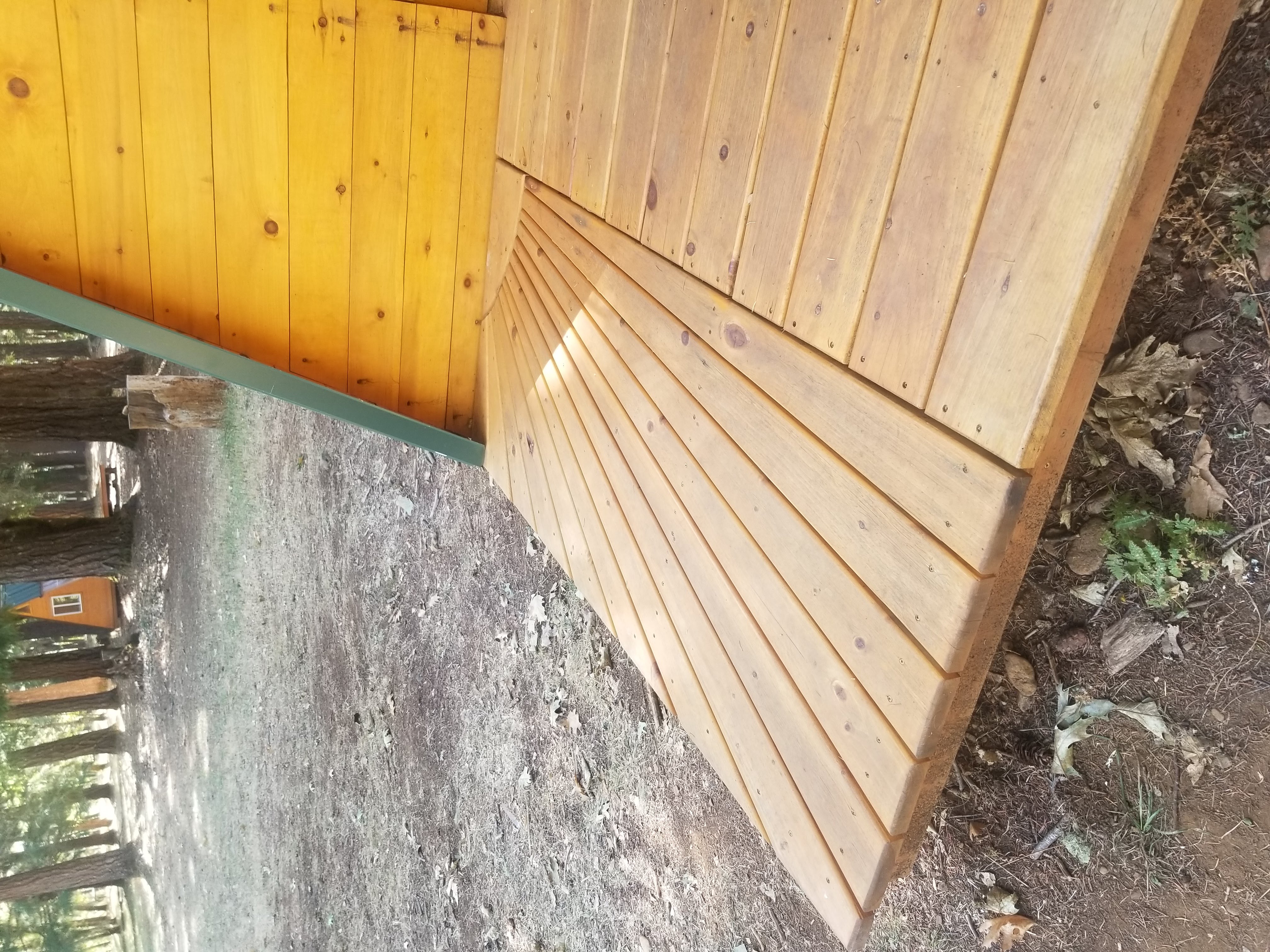 A wooden deck extending outward with mismatched boards