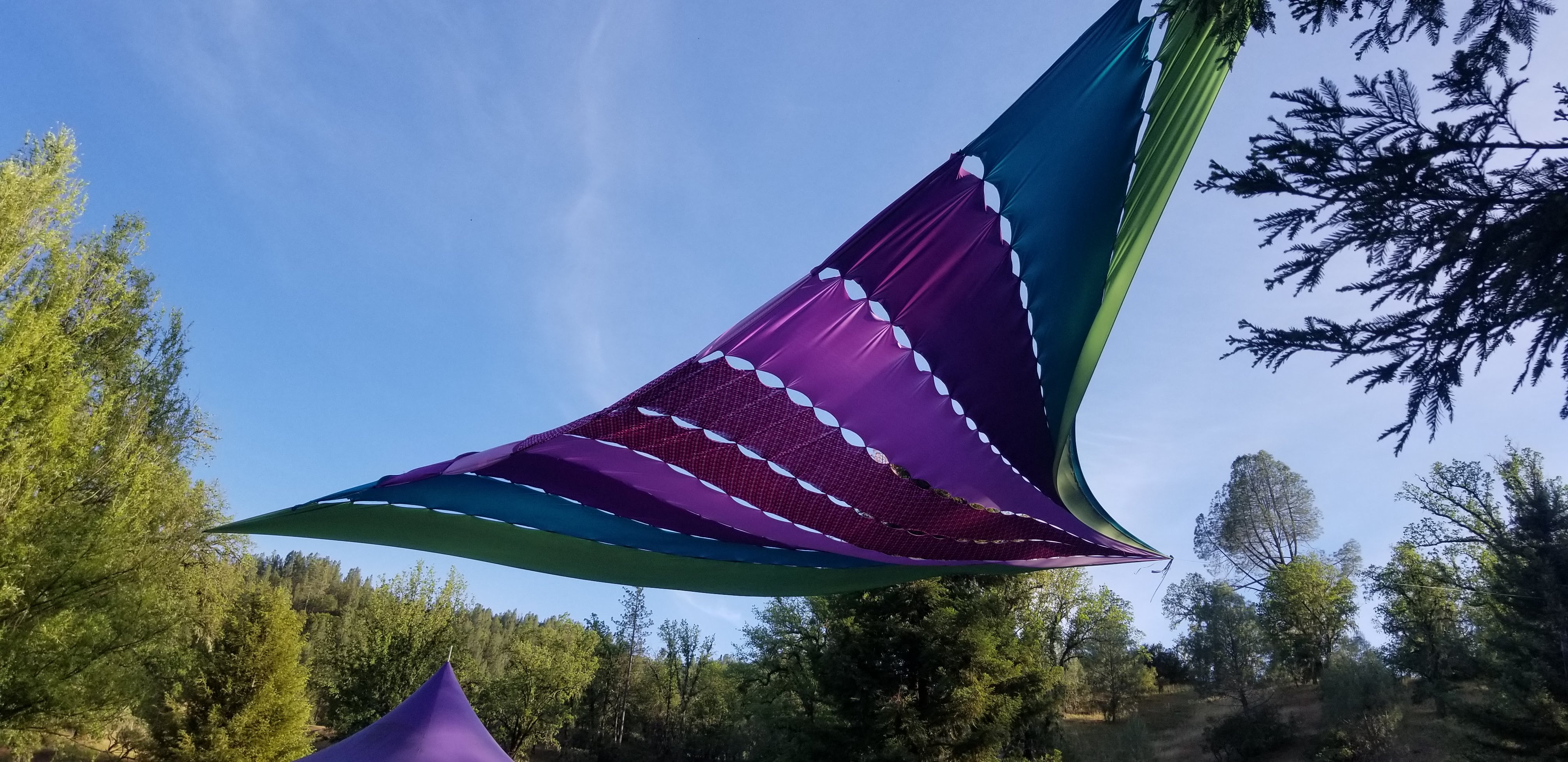 A triangular shade sail stretched between three trees